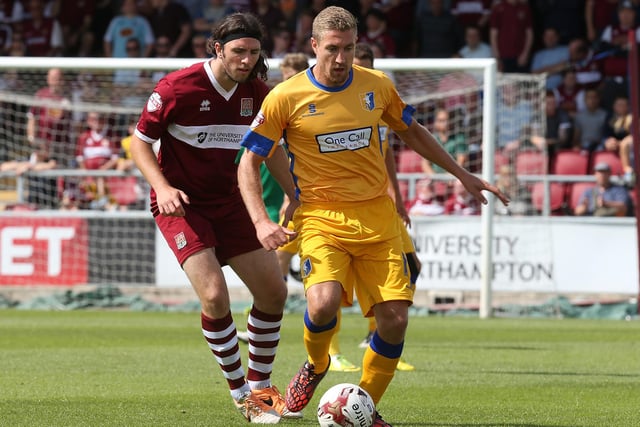Simon Heslop of Mansfield Town looks to play the ball watched by John-Joe O'Toole of Northampton Town during the Sky Bet League Two match between Northampton Town and Mansfield Town at Sixfields on August 9, 2014
