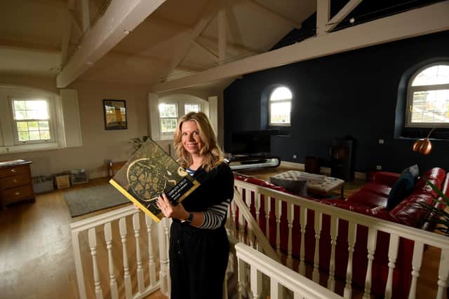 Vivien Strachan pictured holding a book by artist Eric Atkinson in her home on Lombard Street, Rawdon, Leeds