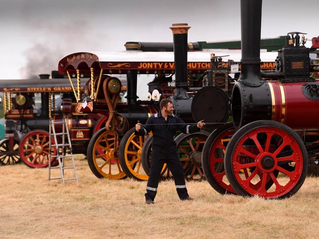 An exhibitor prepares another beautifully restored steam engine as smoke drifts across the rally field