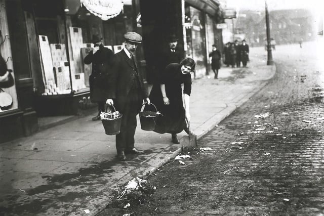 Shopkeepers sweeping up and removing dust and refuse from the roadway outside their premises in Leeds, during the municipal workers strike in December 1913.