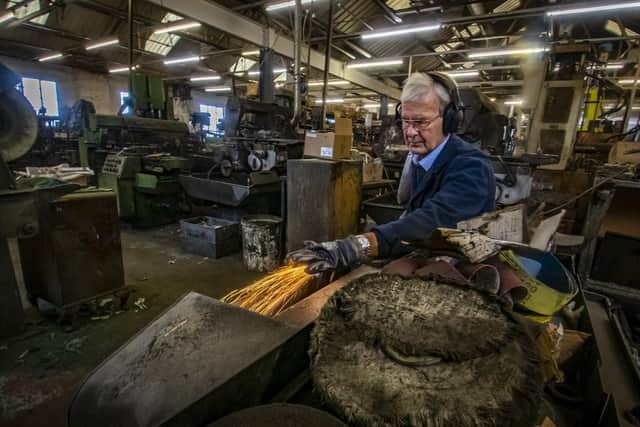 27 September 2022.....   Swordsmith Peter Hopkinson working the swords on the linisher at J. Adams Ltd in Sheffield.
Peter made the ceremonial swords used by the soldiers guarding Queen Elizabeth II coffin as she laid in state at Westminster Hall.  Picture Tony Johnson