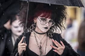 A close up of a goth enthusiast dressed up for the event and shielding from the rain.
