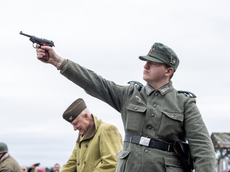 A reenactor wields a gun during a demonstration.