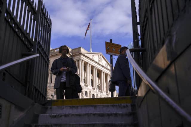 People stand in front of the Bank of England, in the financial district of The City of London, Wednesday, Oct. 12, 2022. The pound sank against the dollar early Wednesday after the Bank of England governor confirmed the bank won't extend an emergency debt-buying plan introduced last month to stabilise financial markets.(AP Photo/Alberto Pezzali)