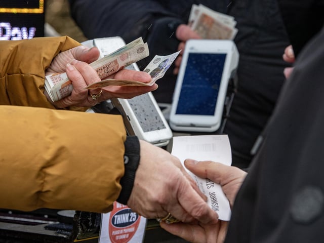 Racegoers take a punt with the course bookmaker at the 505th running of the Kiplingcotes Derby on the Yorkshire Wolds near Market Weighton, the oldest horse race the world, photographed by Tony Johnson for The Yorkshire Post. 21th March 2024