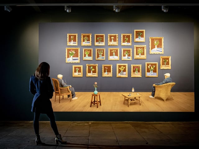 A visitor takes in 'Looking at the Flowers' a photographic drawing printed on 5 panels by David Hockney in his exhibition, 20 Flowers for 2025 and Some Bigger Pictures at Salts Mill in Saltaire. It has a rating of four and a half stars with 1,972 reviews.