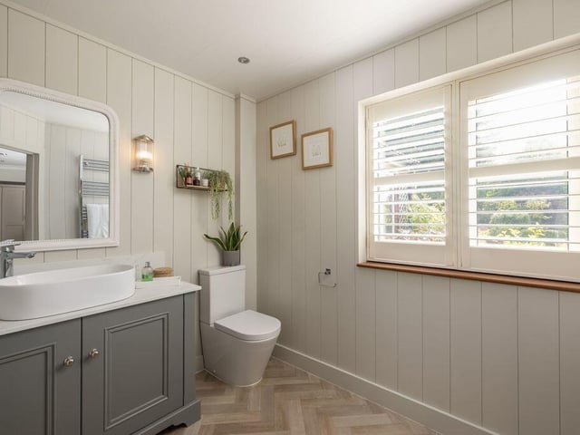 The en-suite has panelled walls and a quartz-topped basin
