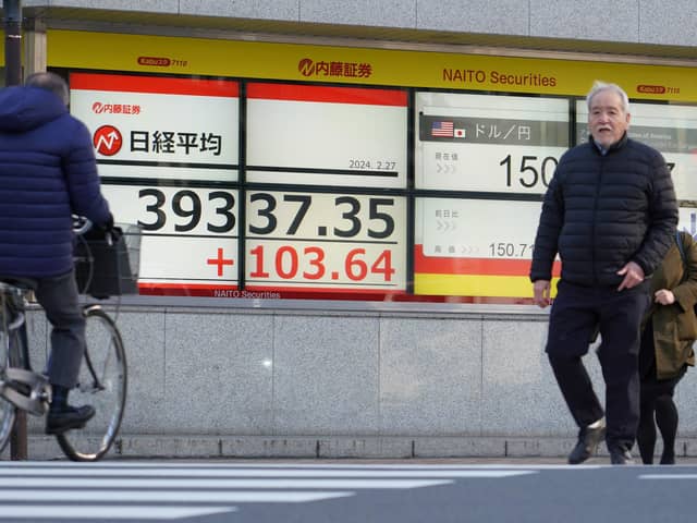People walk past an electronic board displaying a share price of the Nikkei index of the Tokyo Stock Exchange in Tokyo on February 27, 2024. (Photo by Kazuhiro NOGI / AFP)