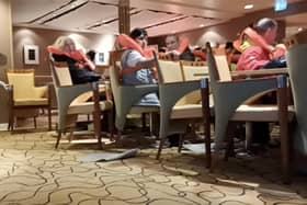 Passengers in life-jackets brace in chairs on board the MS Maud as a rough storm at sea battered the cruise ship on December 21