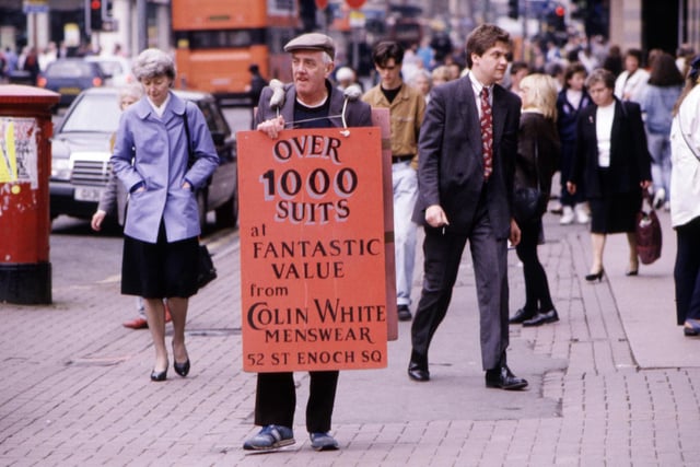 A man wearing a sandwich board advertising suits from Colin White Menswear walks through the city centre Glasgow, August 1990.