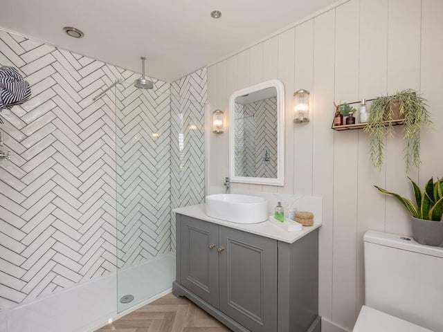 A walk-in shower, vanity unit and heated towel rail feature in the en suite.