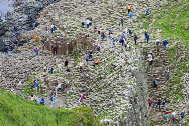 Tourists are pictured at the Giant's Causeway. (Photo by PAUL FAITH / AFP) (Photo by PAUL FAITH/AFP via Getty Images)