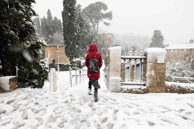 A person walks down a snow-covered street in the mountain village of Valldemossa during a heavy snow-fall, on the Spanish Balearic island of Mallorca, on February 27, 2023. (Photo by JAIME REINA/AFP via Getty Images)