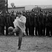 A striking miner kicks a football in front of a line of police officers near the Orgreave coking plant. PIC: Tom Stoddart/Getty Images