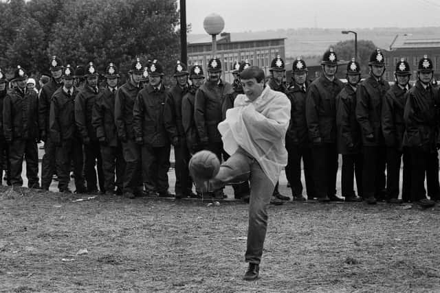 A striking miner kicks a football in front of a line of police officers near the Orgreave coking plant. PIC: Tom Stoddart/Getty Images