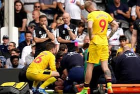 Sheffield United's Chris Basham, bottom, receives treatment as concerned team-mates look on during the defeat at Fulham. Picture: PA.