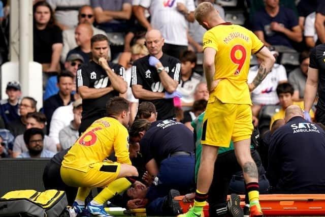 Sheffield United's Chris Basham, bottom, receives treatment as concerned team-mates look on during the defeat at Fulham. Picture: PA.