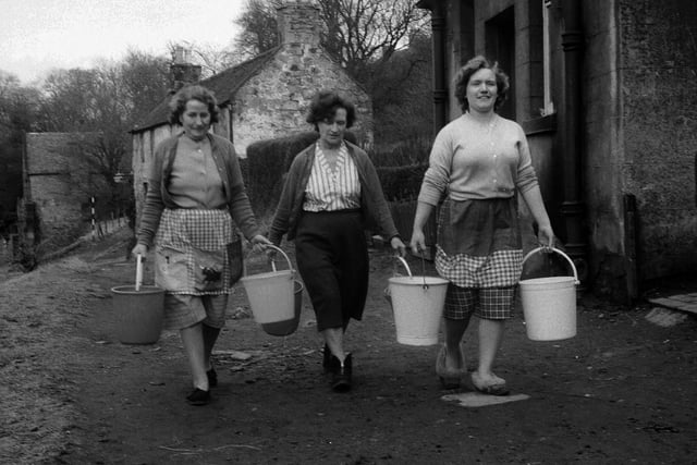 Housewives from Cramond's Caddell Road carry water in buckets after their houses' water supplies were cut off by frozen pipes for two weeks in March 1963.