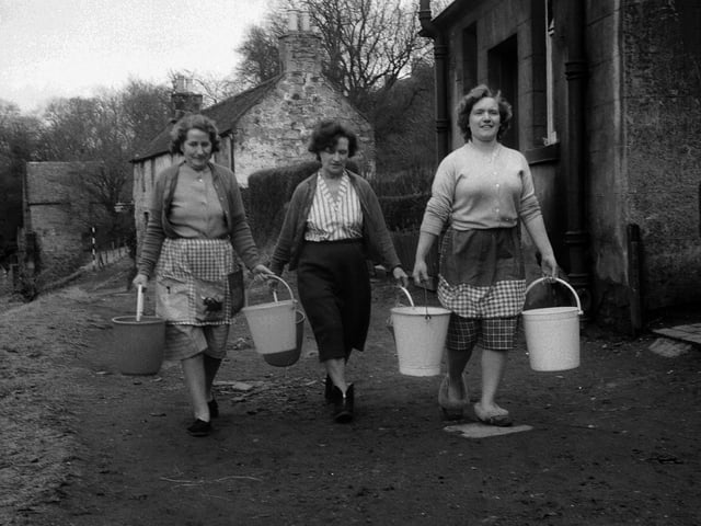 Housewives from Cramond's Caddell Road carry water in buckets after their houses' water supplies were cut off by frozen pipes for two weeks in March 1963.
