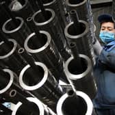 This photo taken on December 15, 2020 shows a worker placing aluminum pistons for vehicle engines on a production line at a machine manufacturing factory in Binzhou, in eastern China's Shandong province. (Photo by STR / AFP)