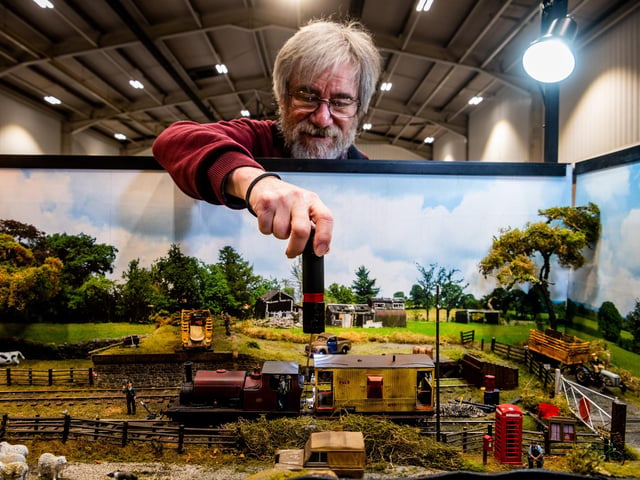 Colin Brown, carefully trying to link a locomotive onto a wagon of the 'Woodhill Goods' Thirsk - 0 Gauge Layout based on The Thirsk and Sowerby Light Railway which is a complete figment of the maker's imagination. However between 1898 and 1906 there was a link between Thirsk Station on the York and Newcastle Railway and the centre of Thirsk and its immediate surroundings including the village of Sowerby where the company built an engine shed to maintain its fleet of locomotives. The final goods-only section to Avenue Sidings, that opened in 1906, was severed by a landslip in 1948 and the line was cut back to Woodhill Goods.