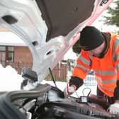 An RAC worker dealing with a breakdown of a car in wintry conditions.