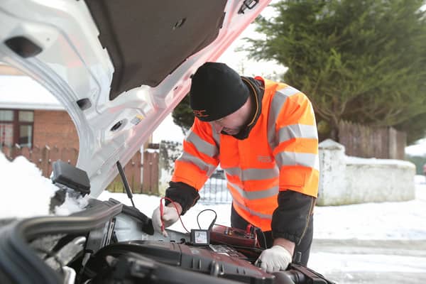 An RAC worker dealing with a breakdown of a car in wintry conditions.