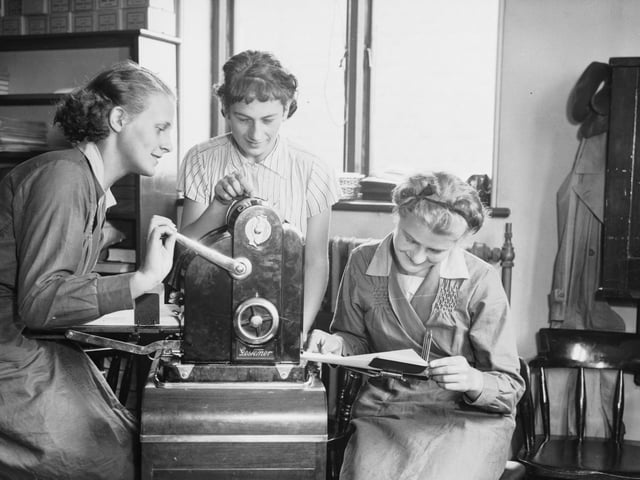 Three female students at the Sheffield Central Day Commercial College learn to operate a duplicating machine for reproducing notes in September 1936.