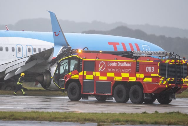 Fire crews and staff by a  Tui plane which has slipped off the runway at Leeds Bradford Airport