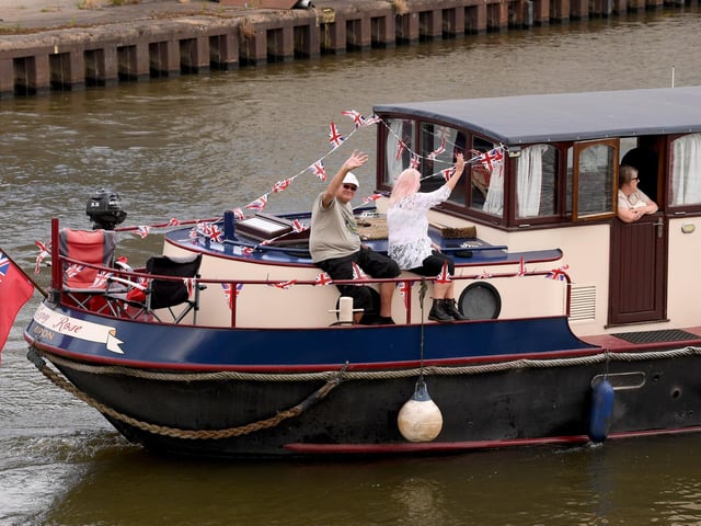 Passengers aboard one of the decorated boats wave to crowds gathered along the dockside as the bicentenary flotilla passes by