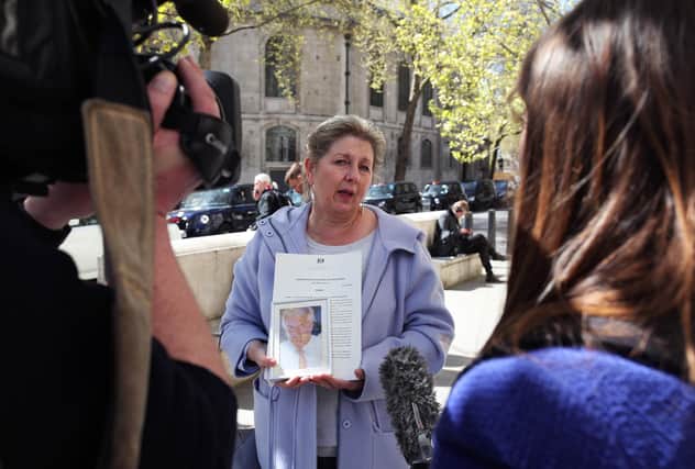 Karen Wilson, widow of postmaster Julian Wilson who died in 2016, holds a photograph of her husband outside the Royal Courts of Justice, London, after his conviction was overturned by the Court of Appeal.