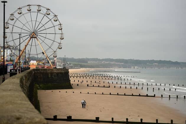 People walk along an empty beach in Bridlington. (Pic credit: Oli Scarff / Getty Images)