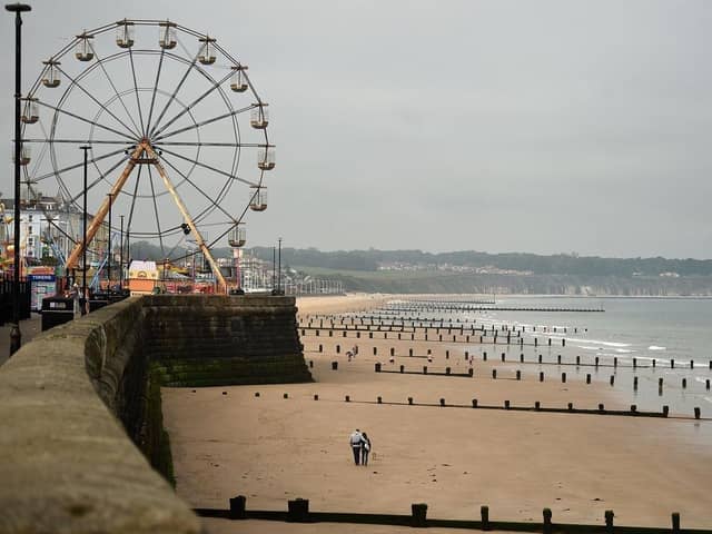 People walk along an empty beach in Bridlington. (Pic credit: Oli Scarff / Getty Images)