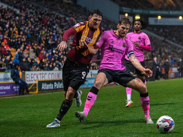 Bradford City's Andy Cook is held off the ball by Northampton captain Jon Guthrie. Picture: Bruce Rollinson