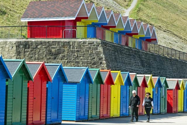 Locals walk past the beach huts on Whitby's West Cliff. (Pic credit: Tony Johnson)