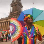 A colourful Pride-goer posed with a rainbow umbrella and fan outside Leeds Town Hall