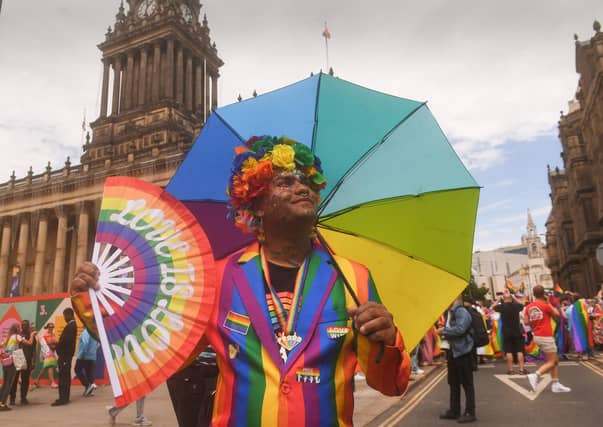 A colourful Pride-goer posed with a rainbow umbrella and fan outside Leeds Town Hall