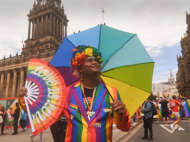 A colourful Pride-goer posed with a rainbow umbrella and fan outside Leeds Town Hall