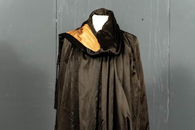 A Black Silk Opera/Evening Cape with caramel coloured silk lining, black silk appliqué trims hung with large tassel drops to each side, attached neck scarf with fringed trim appliqués, smocked detail to the neckline. Sold with black dress. Estimate: £300-500 plus buyer’s premium. Bruce Rollinson