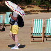 A visitor to Hyde Park, London, shields themself from the sun with a parasol during a heatwave. PIC: Jonathan Brady/PA Wire
