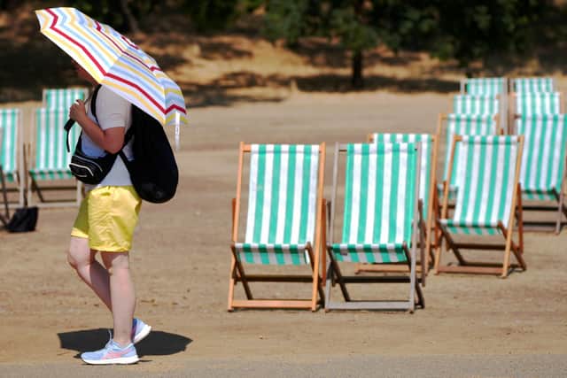 A visitor to Hyde Park, London, shields themself from the sun with a parasol during a heatwave. PIC: Jonathan Brady/PA Wire
