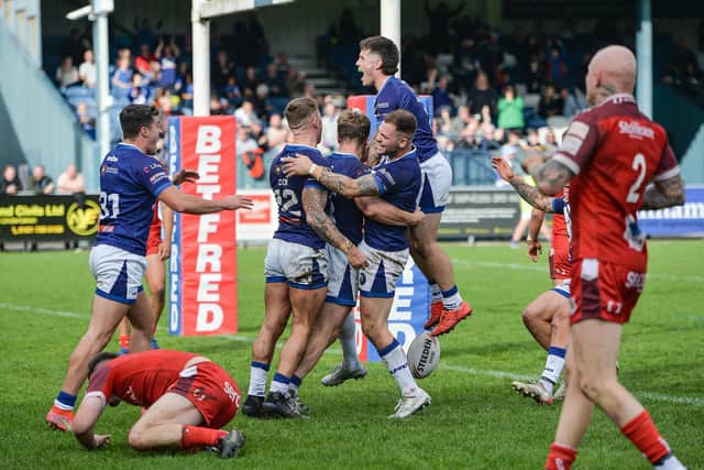 Swinton Lions players celebrate a try in the League One Grand Final on Sunday, leaving the Doncaster players in red, dejected (Picture: Tom Pearson/SWPix.com)