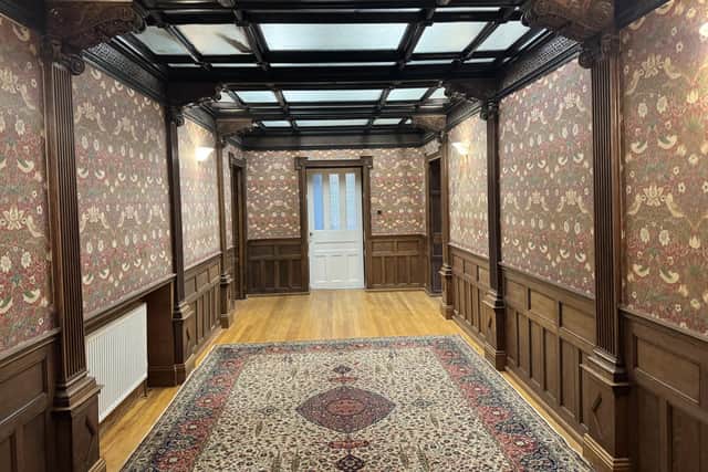A magnificent inner hall in Apartment E at The Hollies features a glass roof, ornate carved timber detailing, panelled walls and William Morris wallpaper.