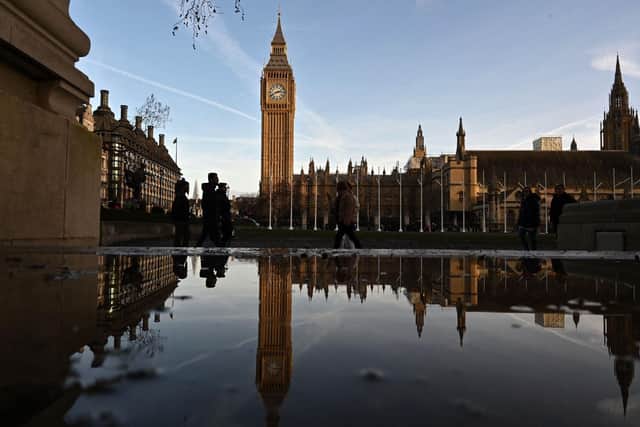 Pedestrians are reflected in a puddle of rain water opposite the Elizabeth Tower and the Palace of Westminster, home to the Houses of Parliament. PIC: JUSTIN TALLIS/AFP via Getty Images