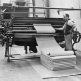 circa 1910:  A man operating a wool drying and folding machine in a textiles mill near Leeds, Yorkshire.  (Photo by Hulton Archive/Getty Images)