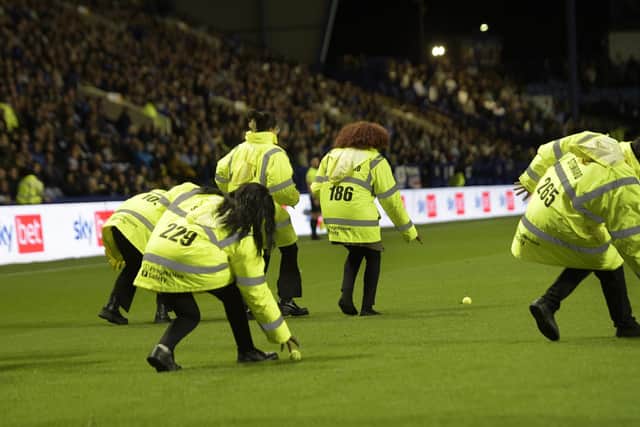 ANGER: Hillsborough stewards clear tennis balls off the pitch after a protest against owner Dejphon Chansiri stops the game against Sunderland