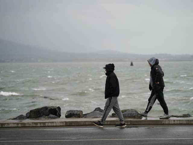 People walk along the seafront as Storm Babet will bring heavy rain to the UK this week, with extensive flooding expected in already-saturated parts of Scotland. Picture: Niall Carson/PA Wire