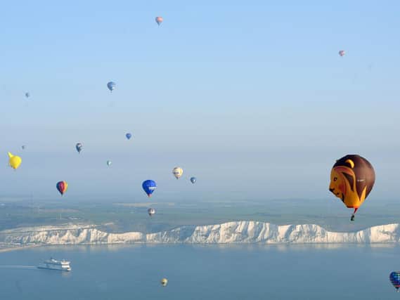 Some of the 100 balloons taking part in a World Record attempt for a mass hot air balloon crossing of the English Channel, fly over the White Cliffs of Dover in Kent.