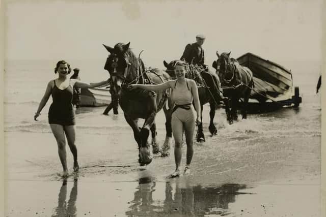 Holidaymakers at Filey delight to give a hand to the boatmen and help the horses to drag the big boats in from the sea.
