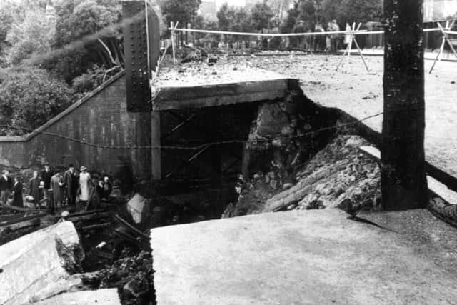 A crowd survey damage to railway lines and a bridge